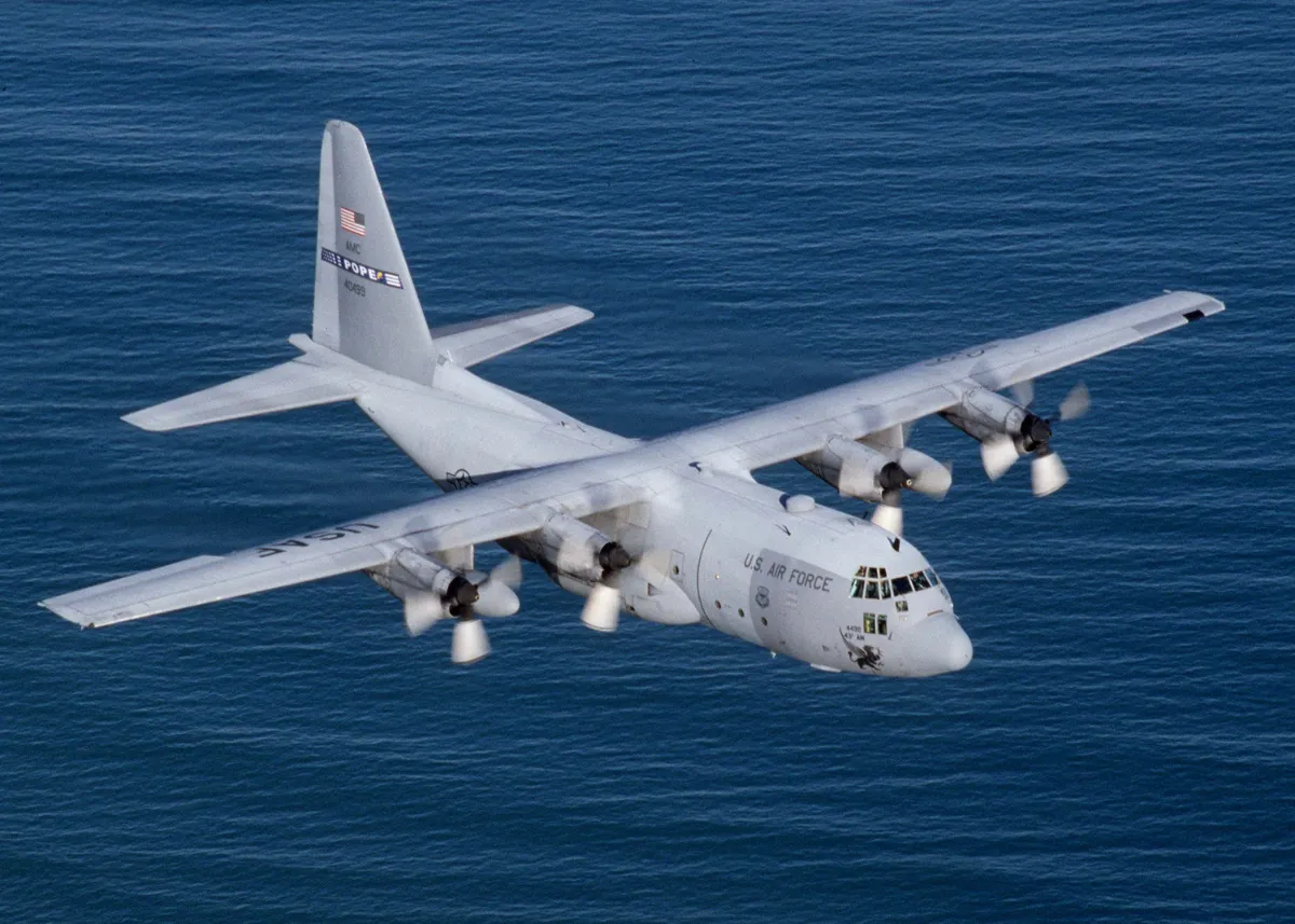 Representative Lockheed C-130E Hercules flying over the ocean.