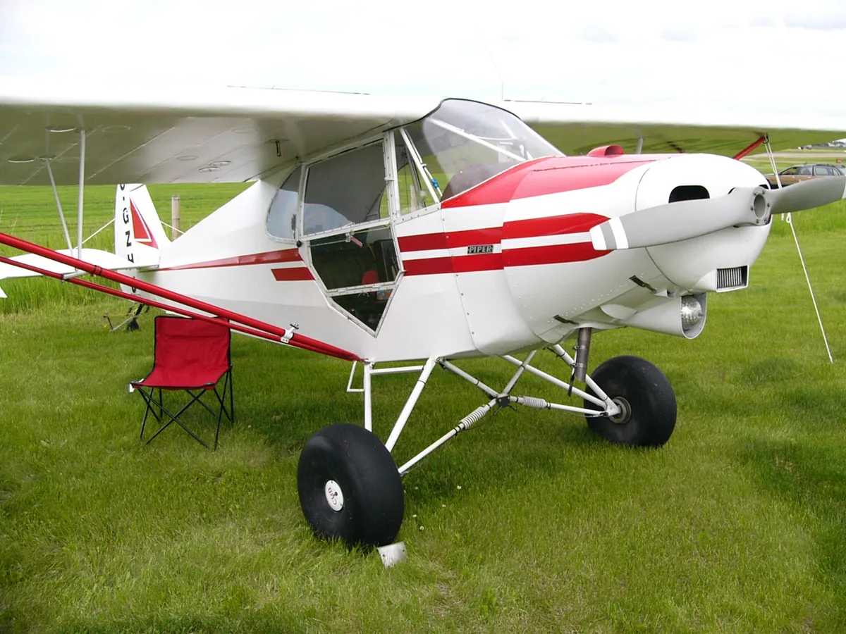 Representative modified Piper J-5AX parked on grass with its cabin door open.